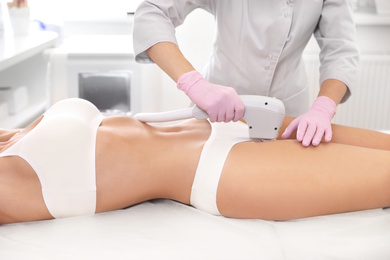 Photo of Young woman undergoing laser epilation procedure in beauty salon, closeup