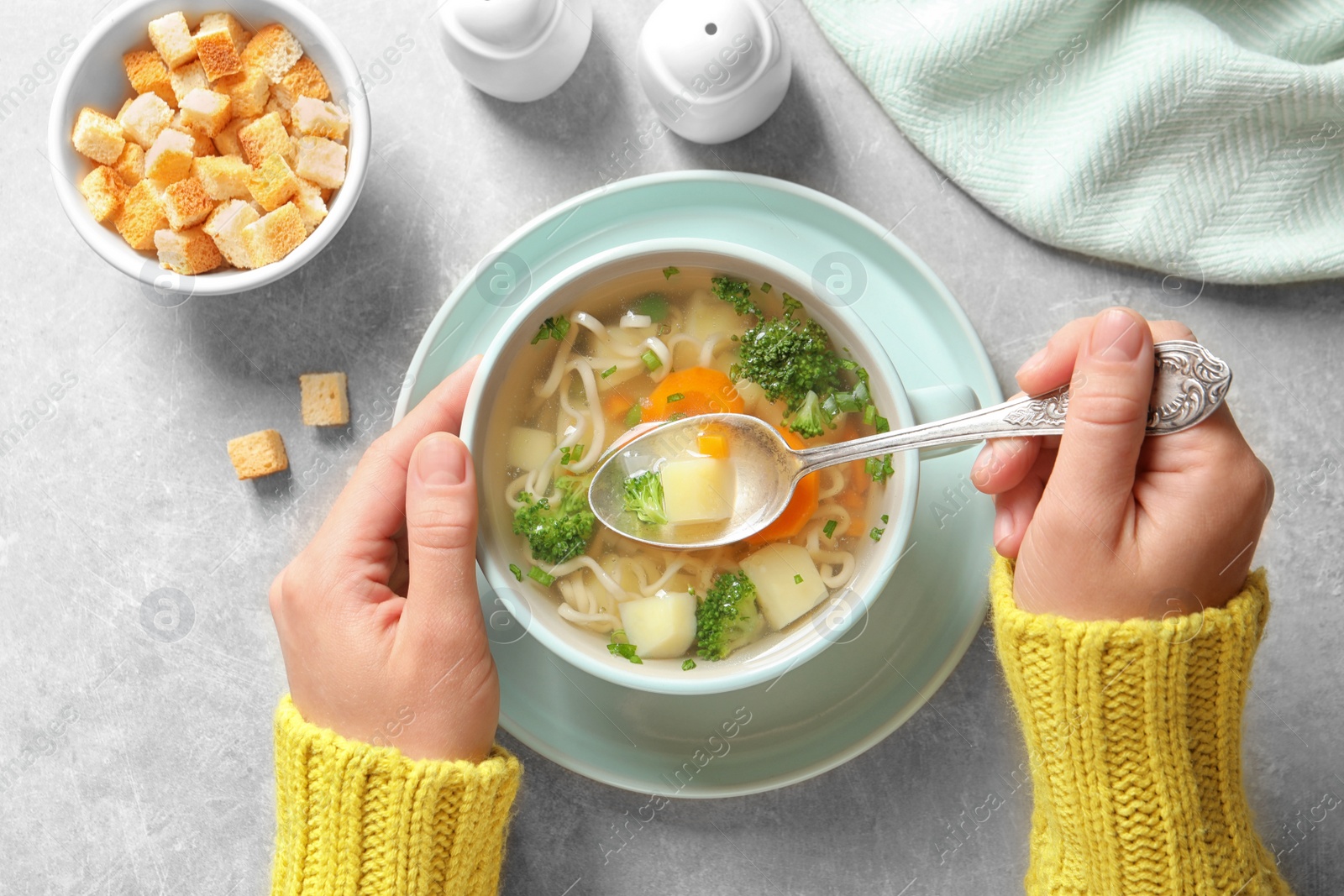 Photo of Woman eating fresh homemade vegetable soup at grey table, top view