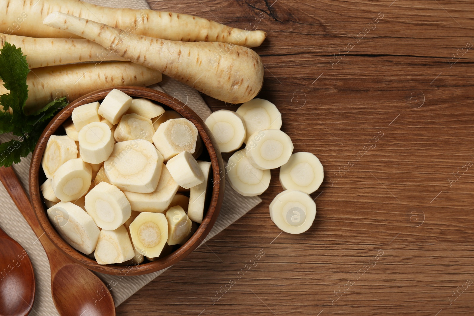 Photo of Flat lay composition with whole and cut fresh ripe parsnips on wooden table. Space for text