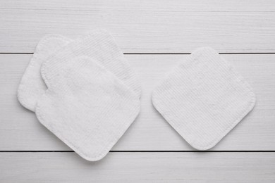 Photo of Clean cotton pads on white wooden table, flat lay
