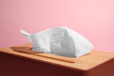 Holder with paper tissues on pink background, closeup