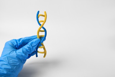Photo of Scientist holding DNA molecule model made of colorful plasticine on white background, closeup. Space for text
