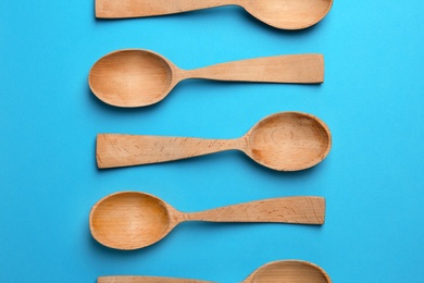 Photo of Clean empty wooden spoons on blue background, flat lay