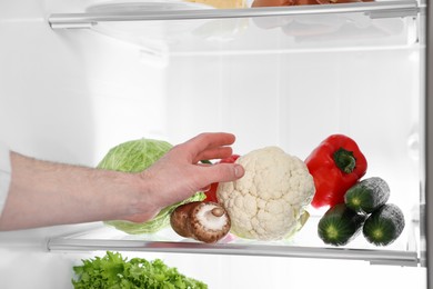 Photo of Man taking cauliflower out of refrigerator, closeup