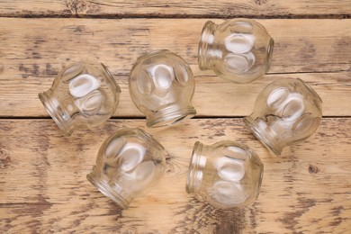 Photo of Glass cups on wooden table, flat lay. Cupping therapy