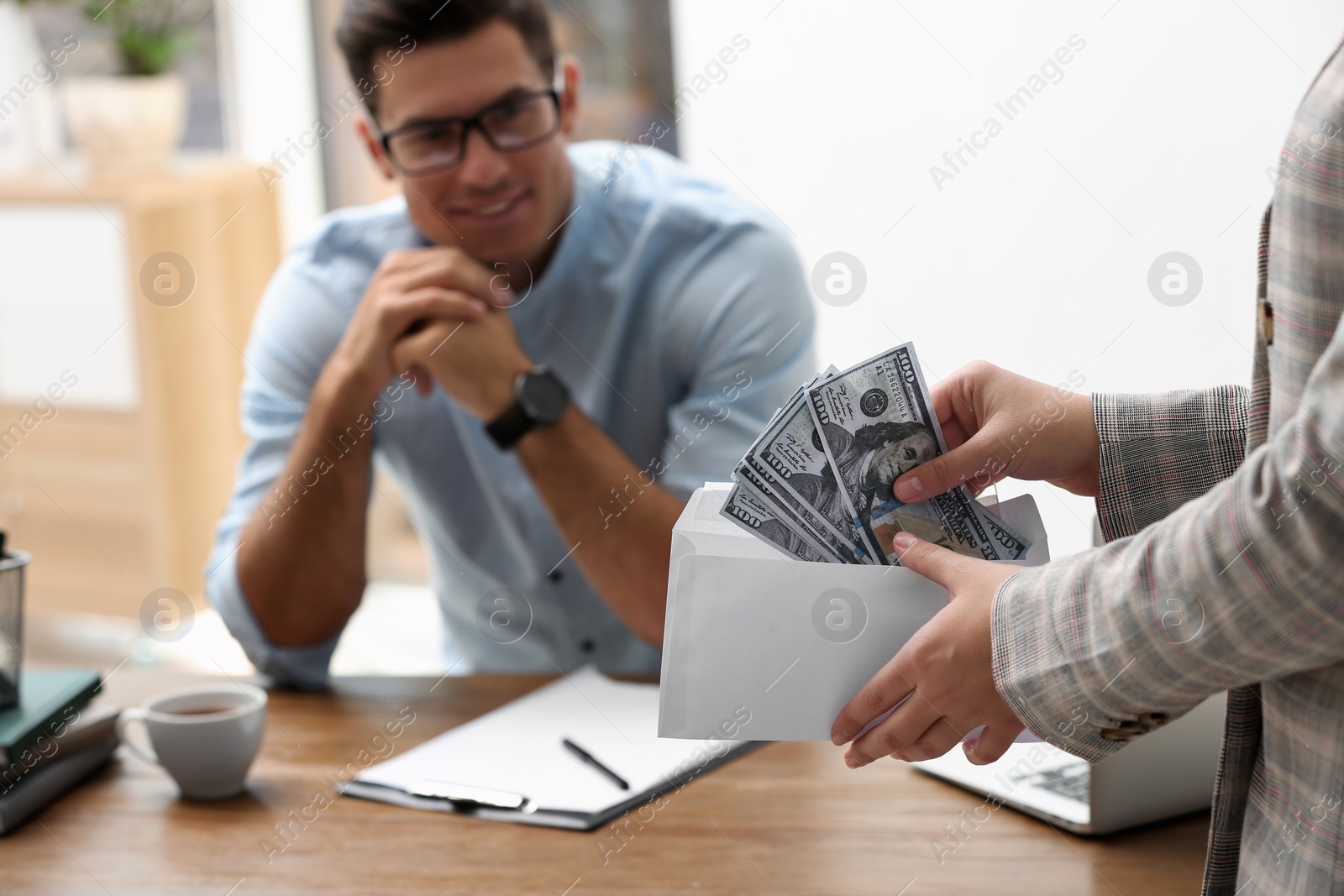 Photo of Woman offering bribe money to man at table, closeup