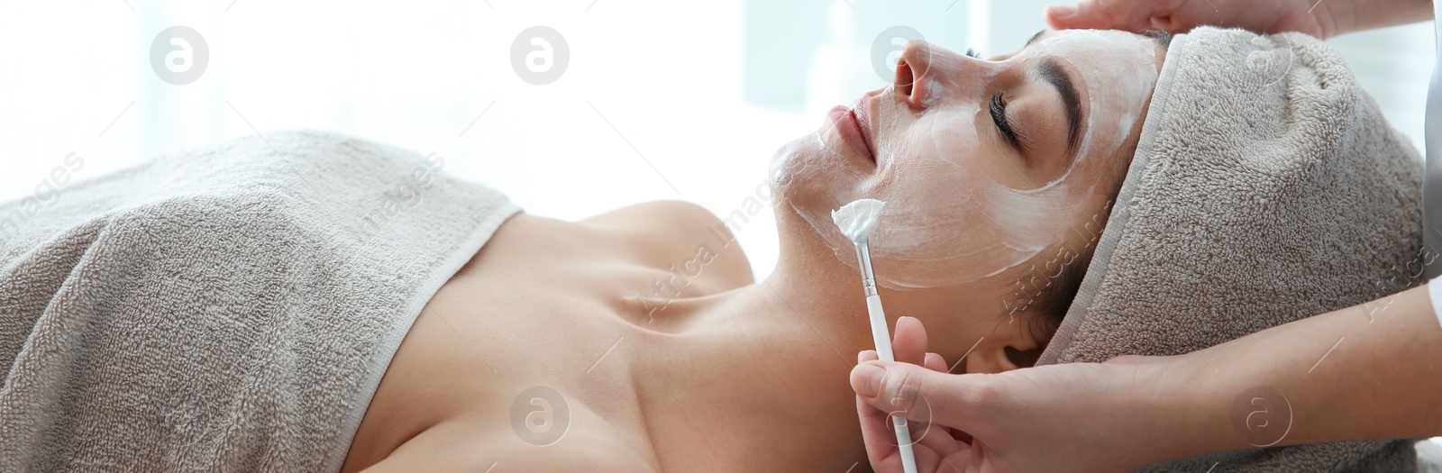 Image of Cosmetologist applying mask on client's face in spa salon. Banner design