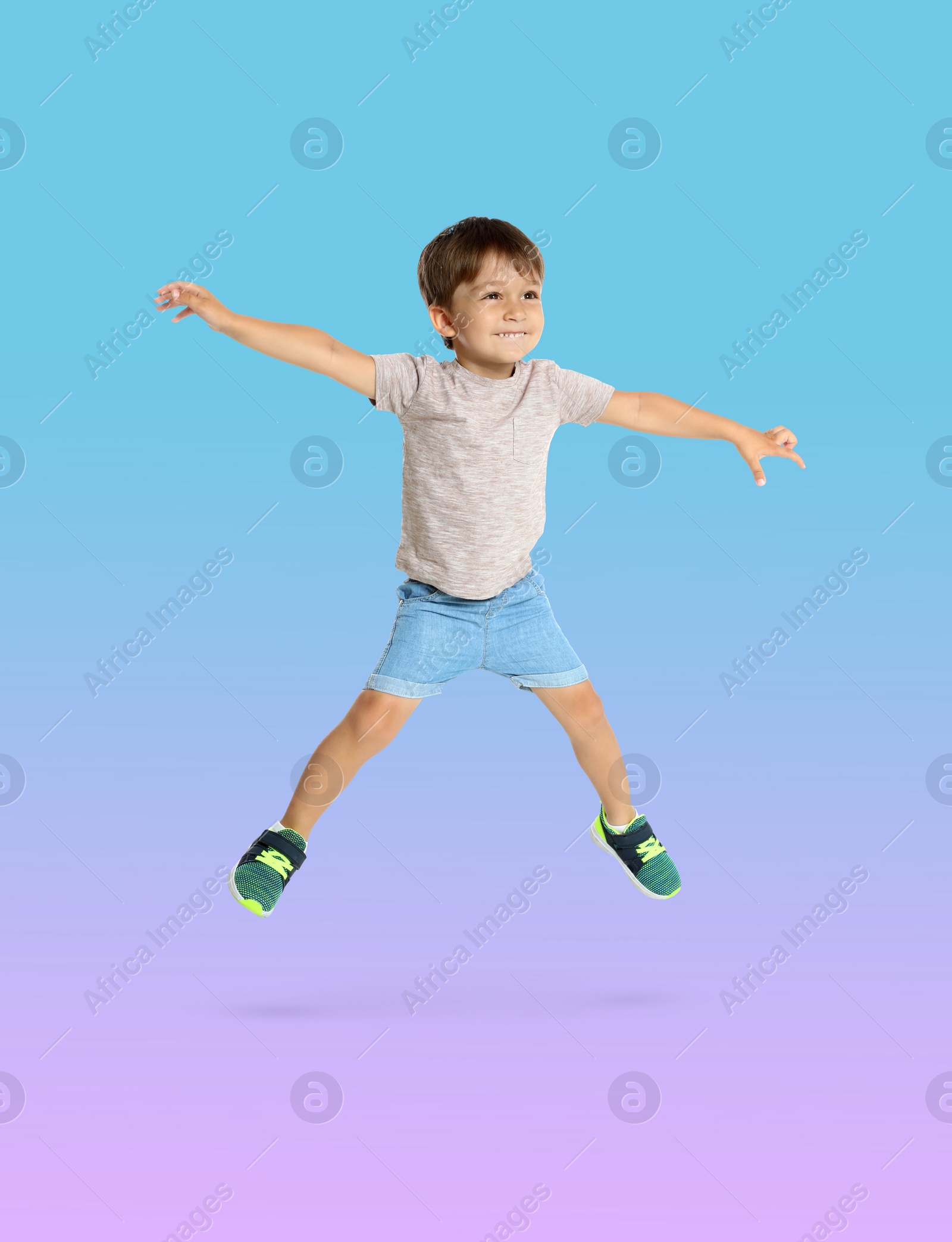 Image of Happy boy jumping on color gradient background