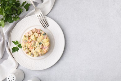 Photo of Tasty Olivier salad with boiled sausage served on light grey table, flat lay. Space for text