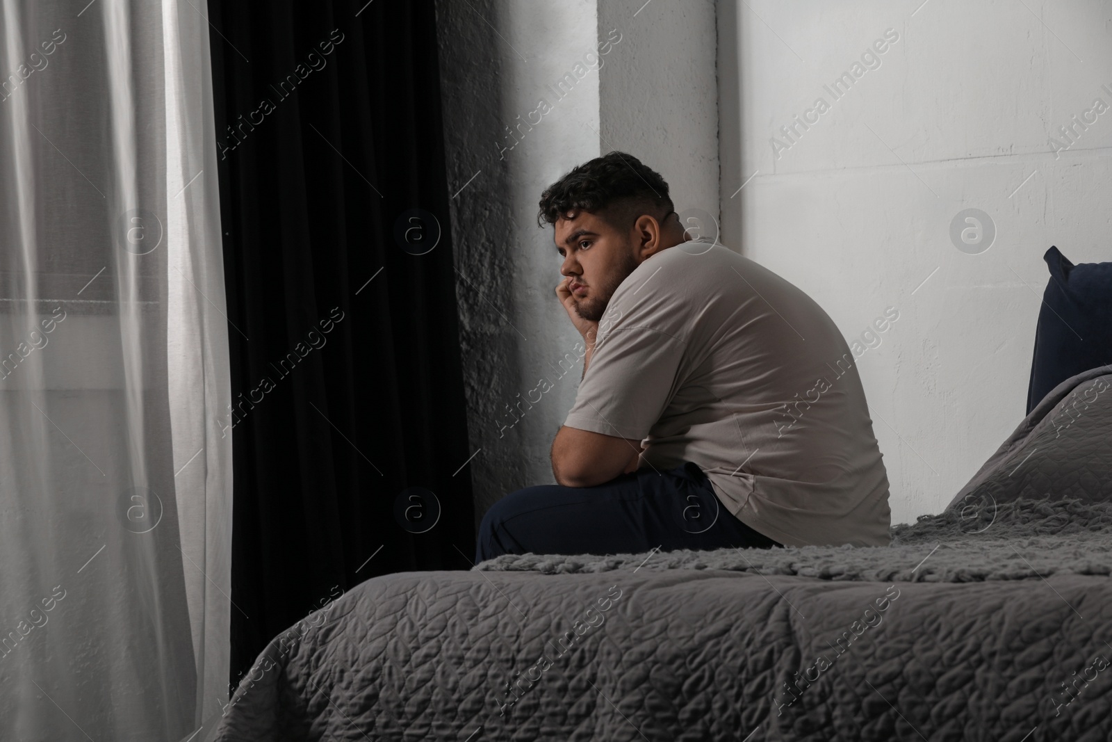 Photo of Depressed overweight man on bed at home