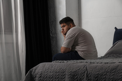 Photo of Depressed overweight man on bed at home
