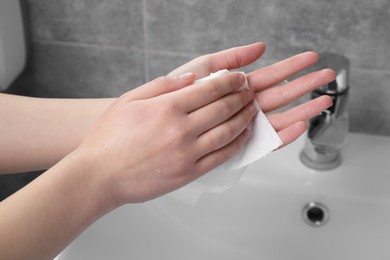 Photo of Woman wiping hands with paper towel in bathroom, closeup