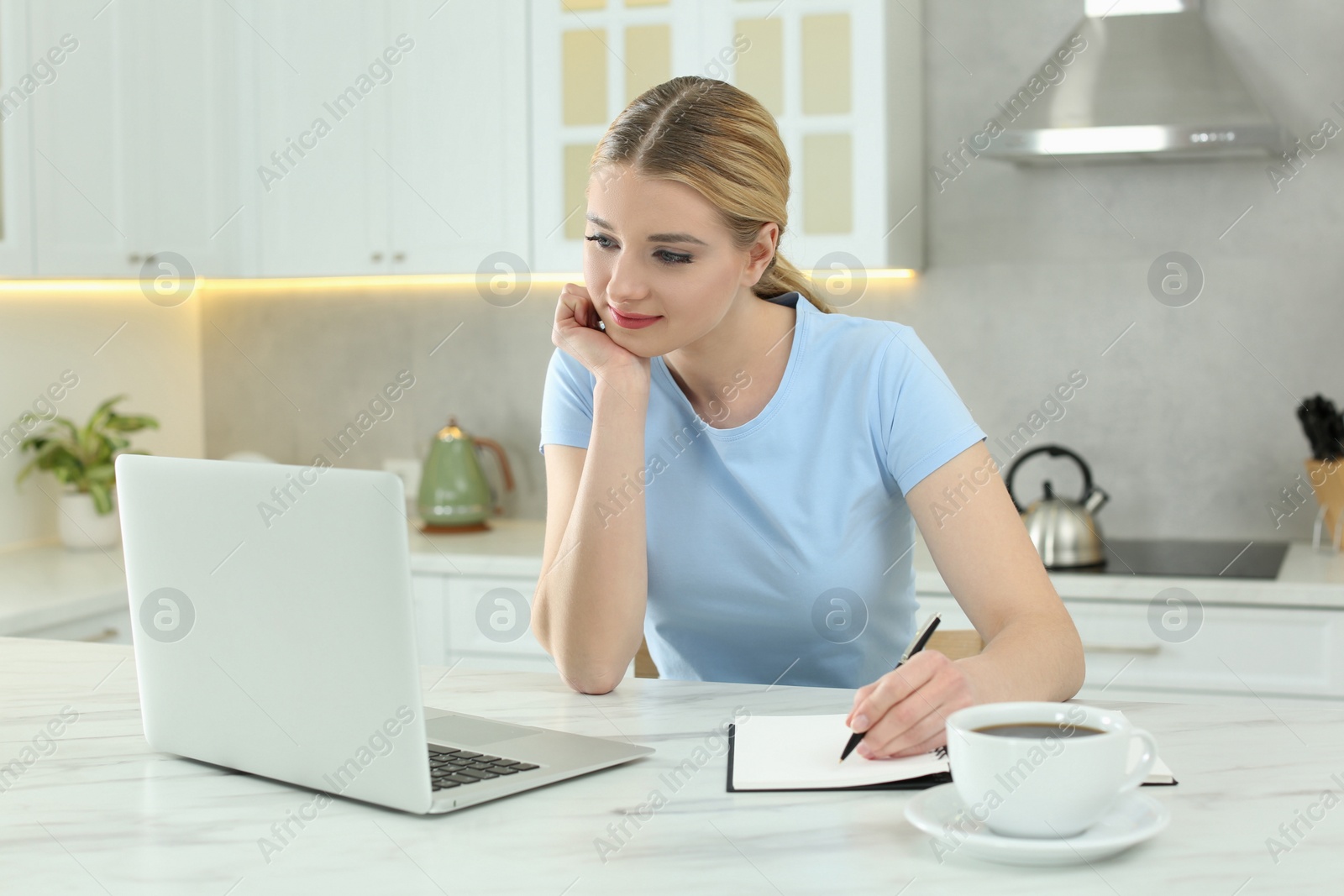 Photo of Home workplace. Woman working on laptop at marble desk in kitchen