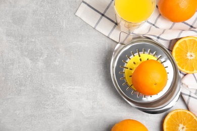 Photo of Fresh ripe oranges, juice and squeezer on grey table, flat lay. Space for text