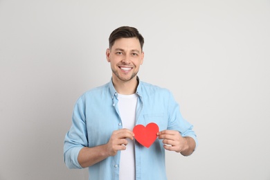 Photo of Portrait of man with paper heart on light background