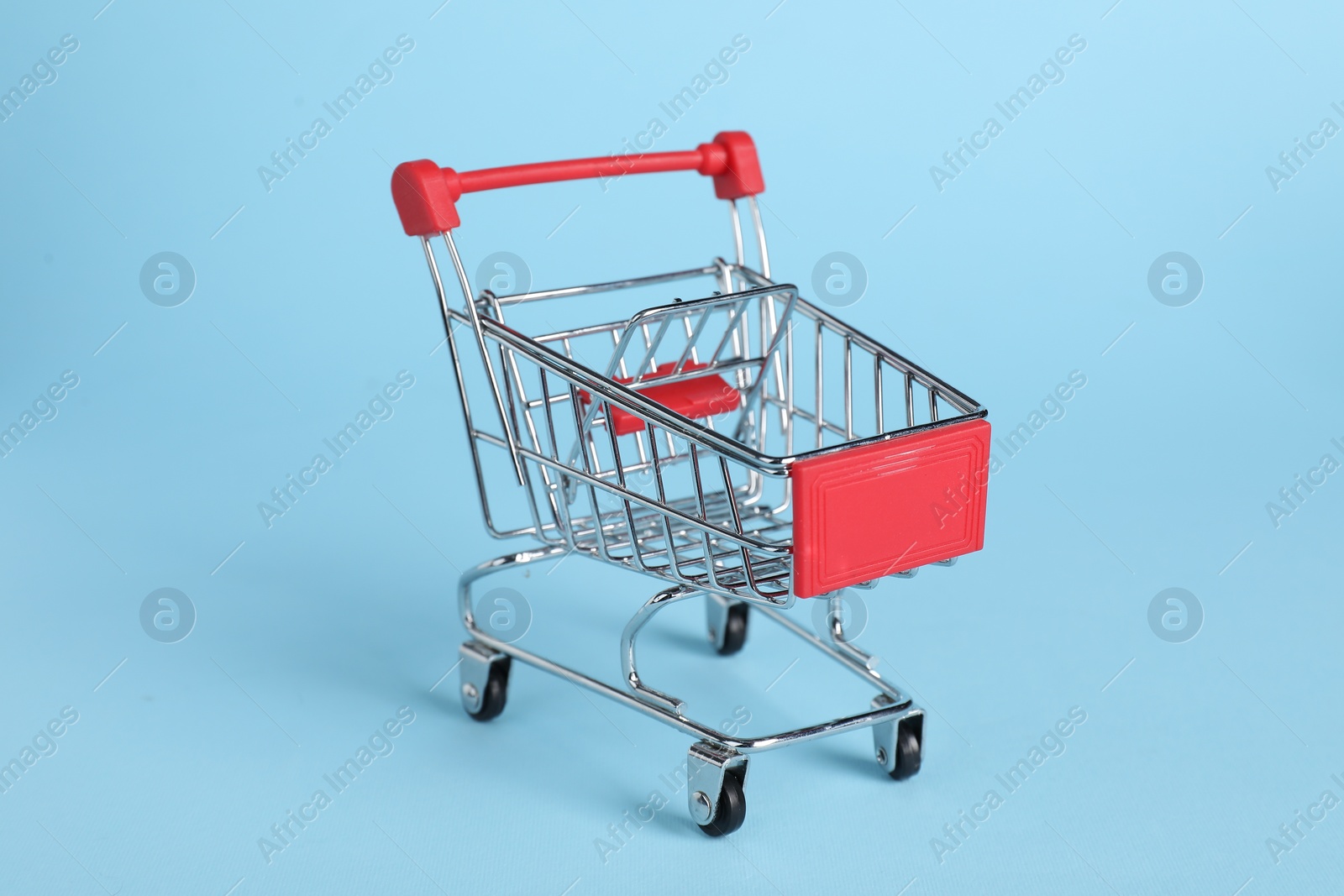 Photo of Small metal shopping cart on light blue background