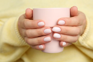 Woman with white nail polish holding cup, closeup