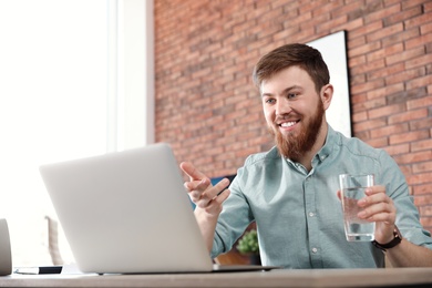 Young man using video chat on laptop in home office