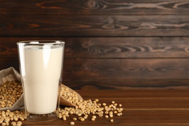 Photo of Fresh soy milk and beans on wooden table, space for text