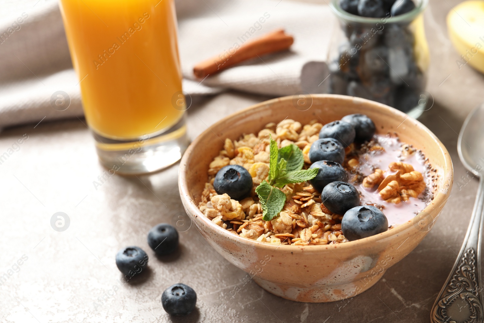 Photo of Bowl of tasty oatmeal with blueberries and yogurt on marble table