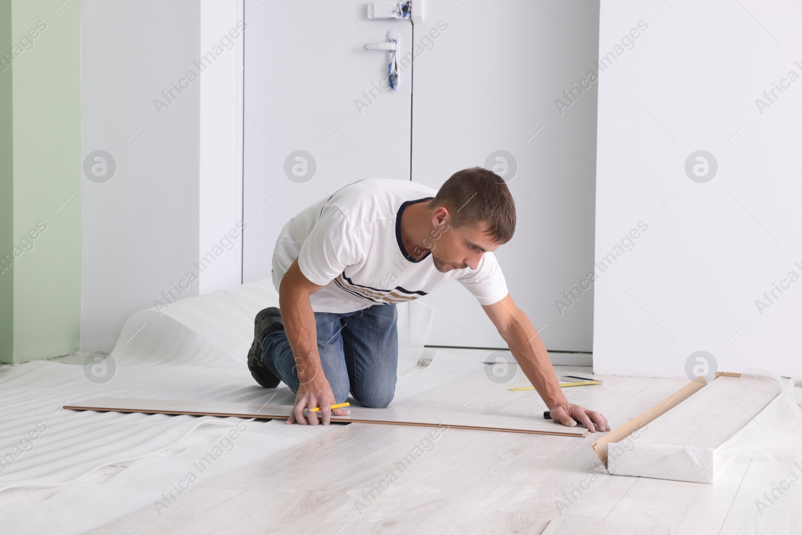 Photo of Man installing new laminate flooring in room