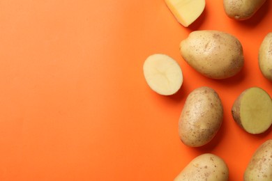 Photo of Fresh raw potatoes on orange background, flat lay. Space for text