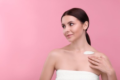 Photo of Beautiful woman with smear of body cream on her collarbone against pink background, space for text