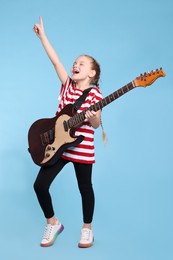 Photo of Cute girl with electric guitar on light blue background