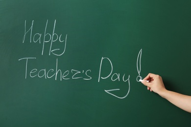 Photo of Woman writing HAPPY TEACHER'S DAY on green chalkboard, closeup view