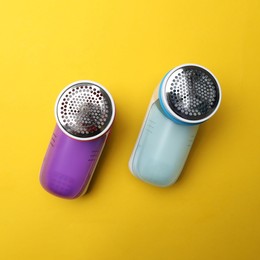 Photo of Modern fabric shavers on yellow background, flat lay