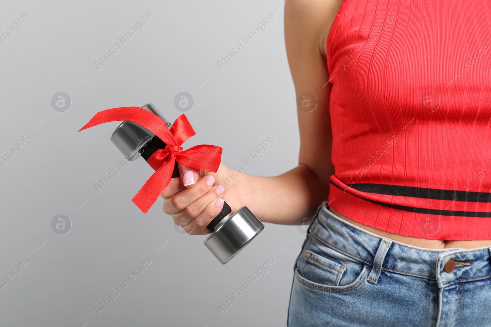 Photo of Woman with dumbbell as symbol of girl power on light grey background, closeup. 8 March concept