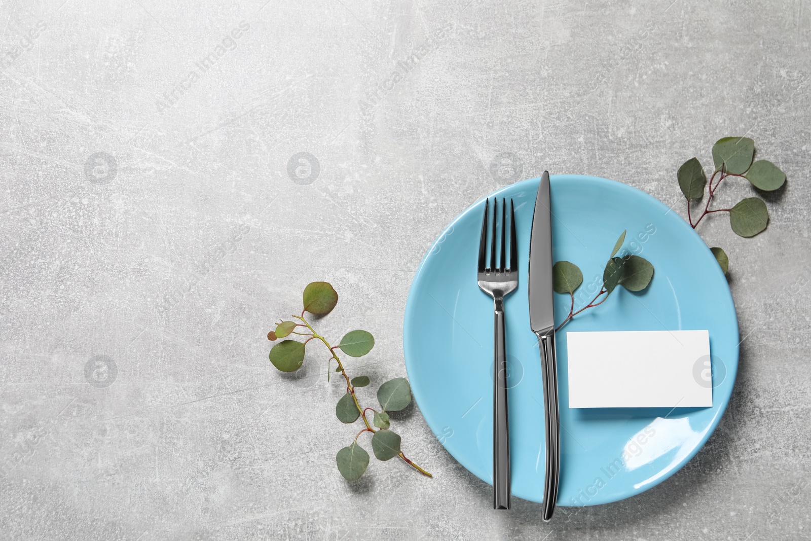 Photo of Stylish table setting with cutlery and eucalyptus leaves, flat lay. Space for text