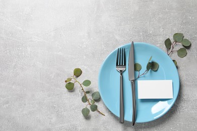 Photo of Stylish table setting with cutlery and eucalyptus leaves, flat lay. Space for text