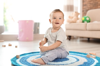 Photo of Adorable little baby playing with wooden blocks at home