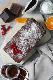 Photo of Tasty chocolate sponge cake and ingredients on light grey table, flat lay