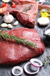 Photo of Fresh raw beef cuts and different spices on grey textured table