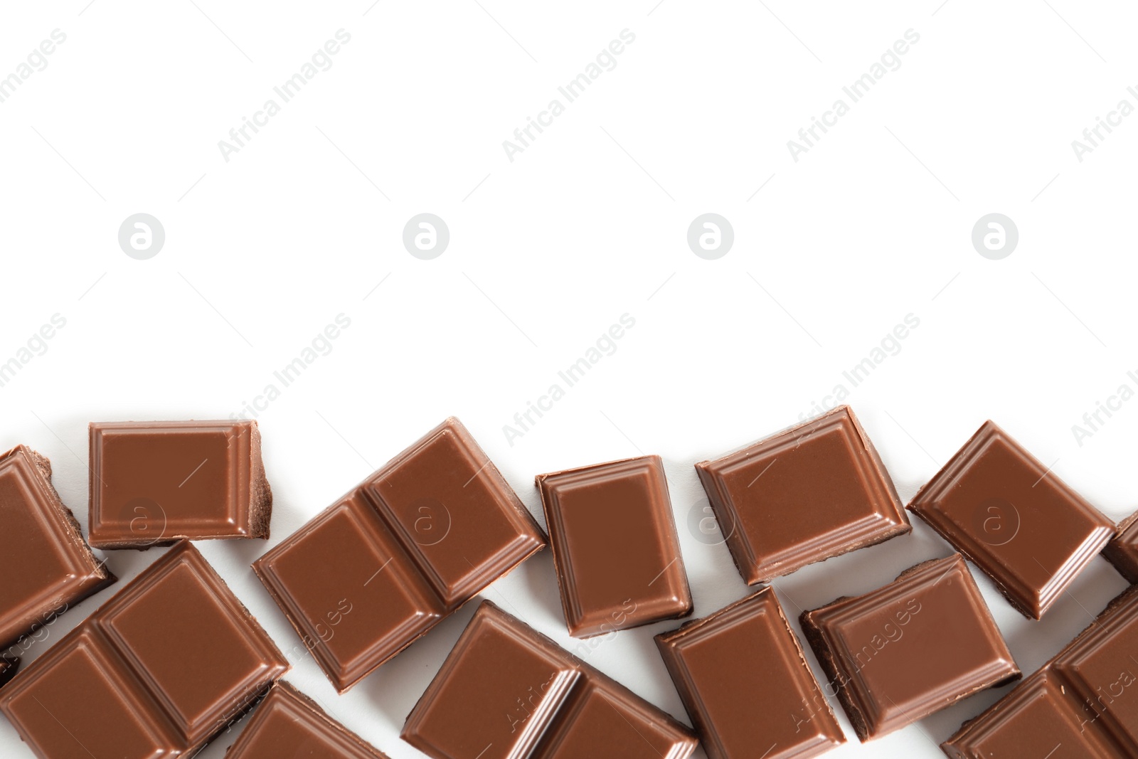 Photo of Pieces of tasty milk chocolate on white background, top view. Space for text