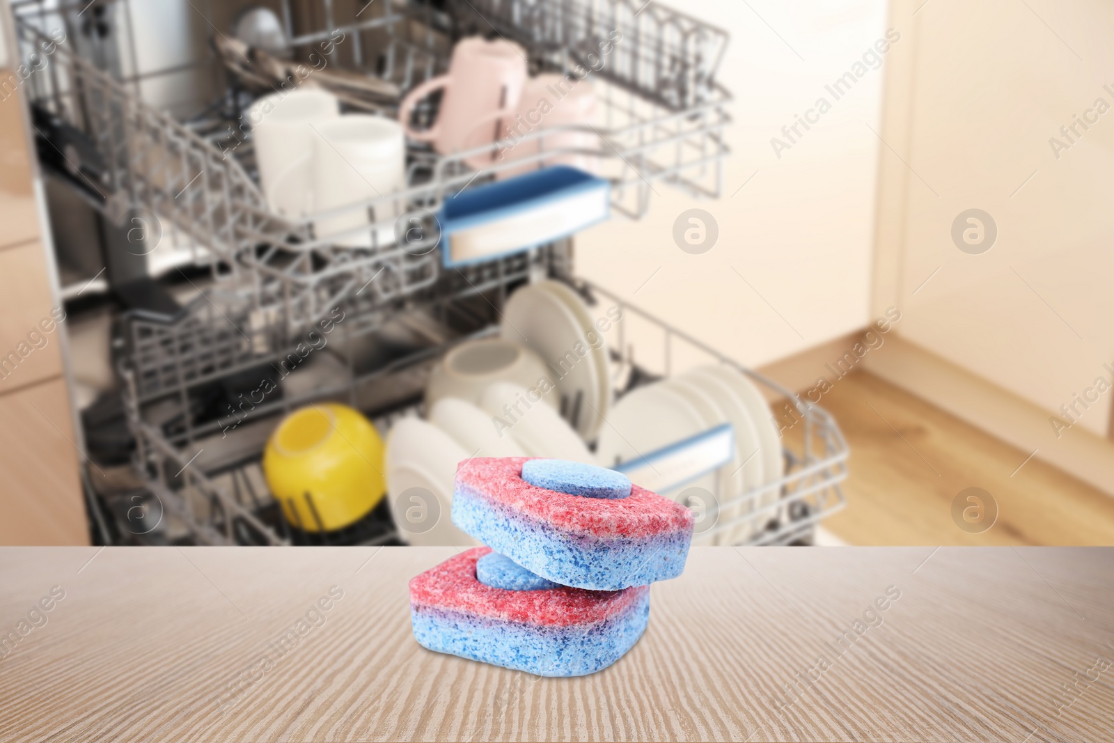 Image of Two dishwasher detergent tablets on wooden table in kitchen