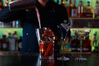 Bartender making fresh alcoholic cocktail at counter in bar, selective focus