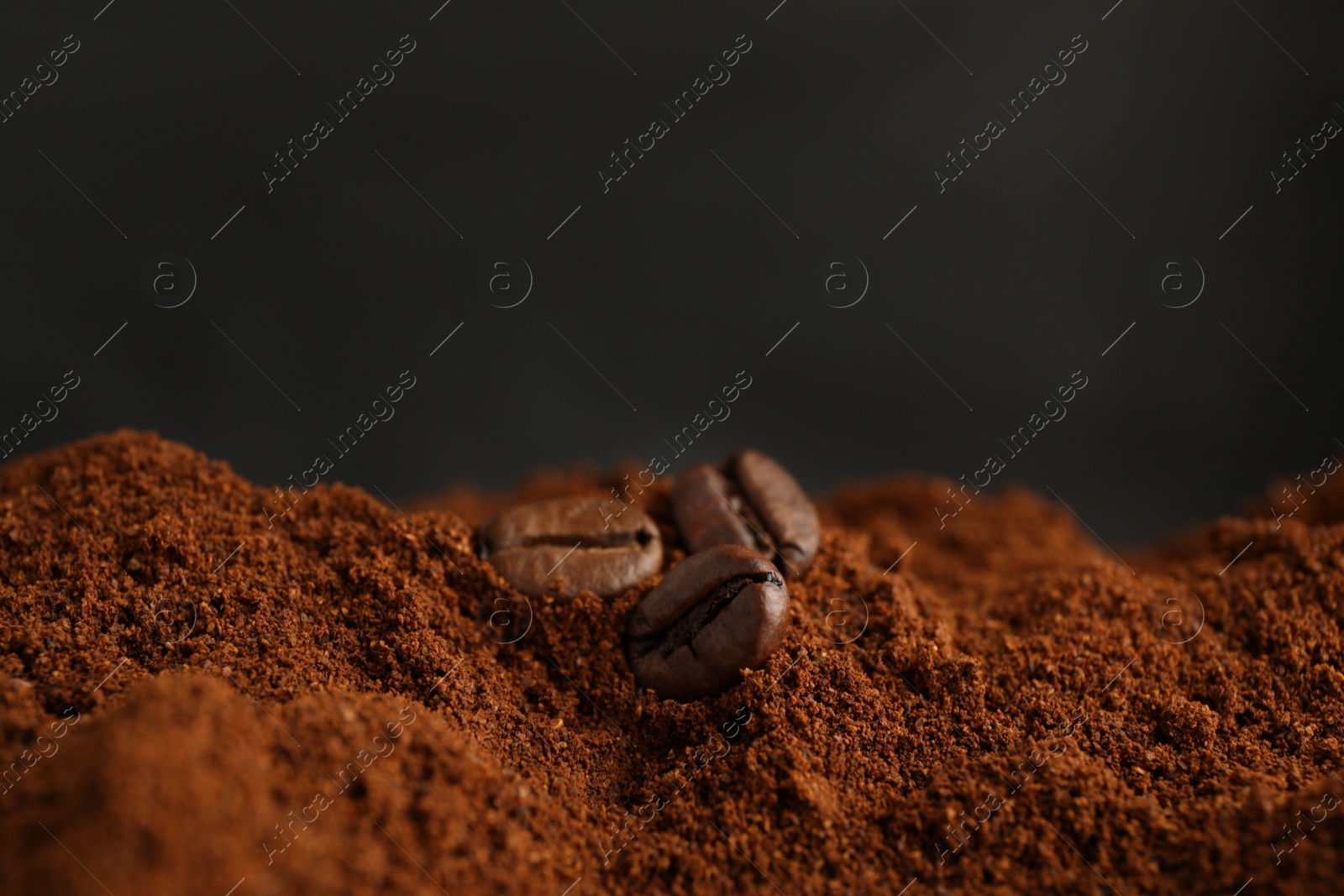 Photo of Coffee grounds and roasted beans on dark background, closeup