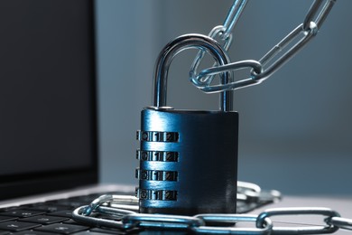 Photo of Cyber security. Metal combination padlock with chain on laptop, closeup