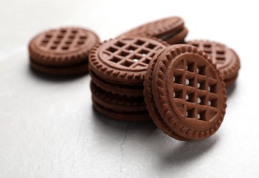 Photo of Tasty chocolate sandwich cookies with cream on light grey table, closeup