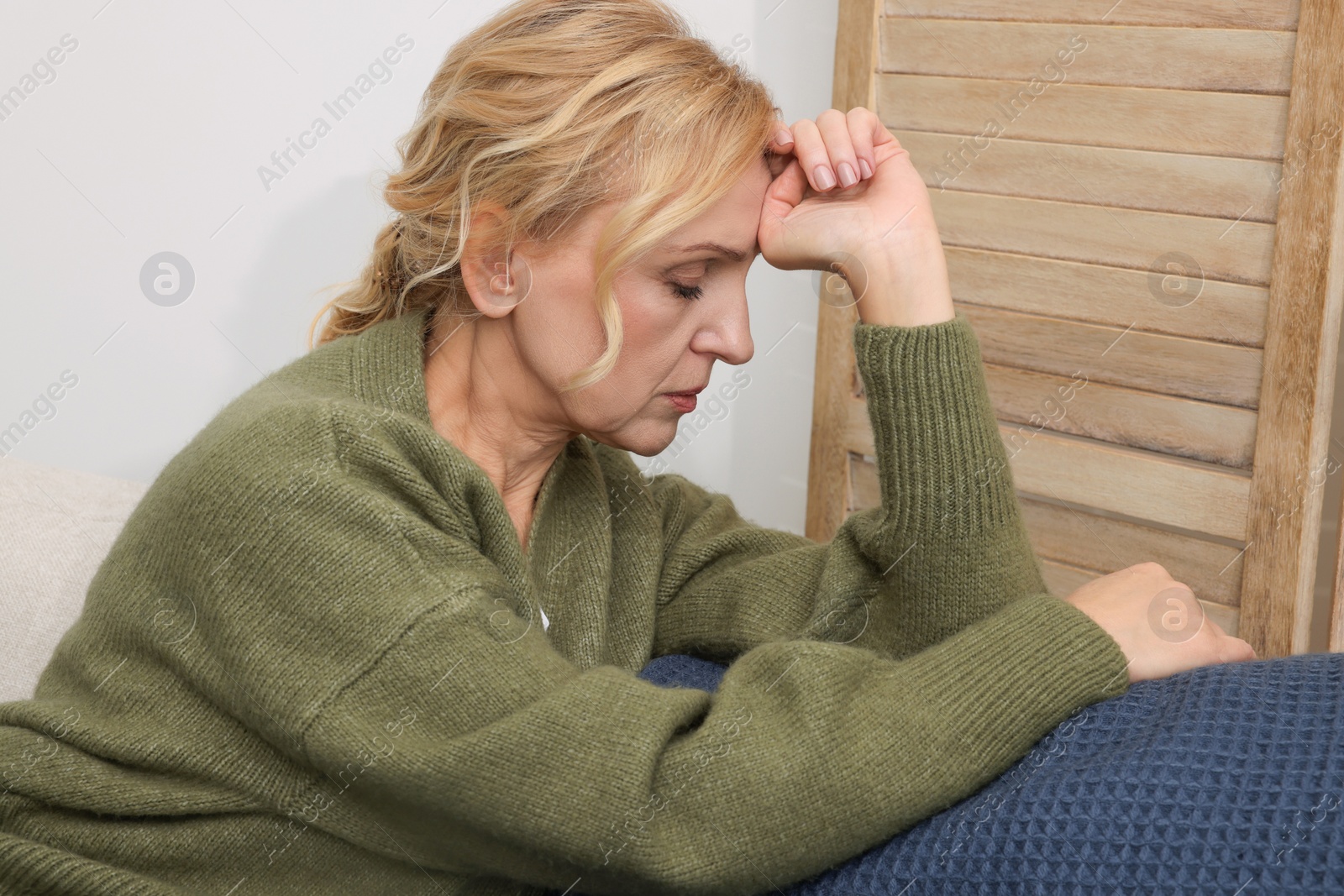 Photo of Upset middle aged woman sulking on sofa at home. Loneliness concept