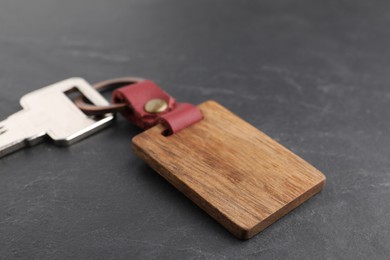 Photo of Key and wooden keychain with Ukrainian coat of arms on grey background, closeup