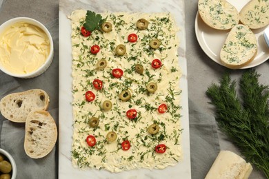 Photo of Fresh butter board with cut olives, dill and bread on grey table, flat lay