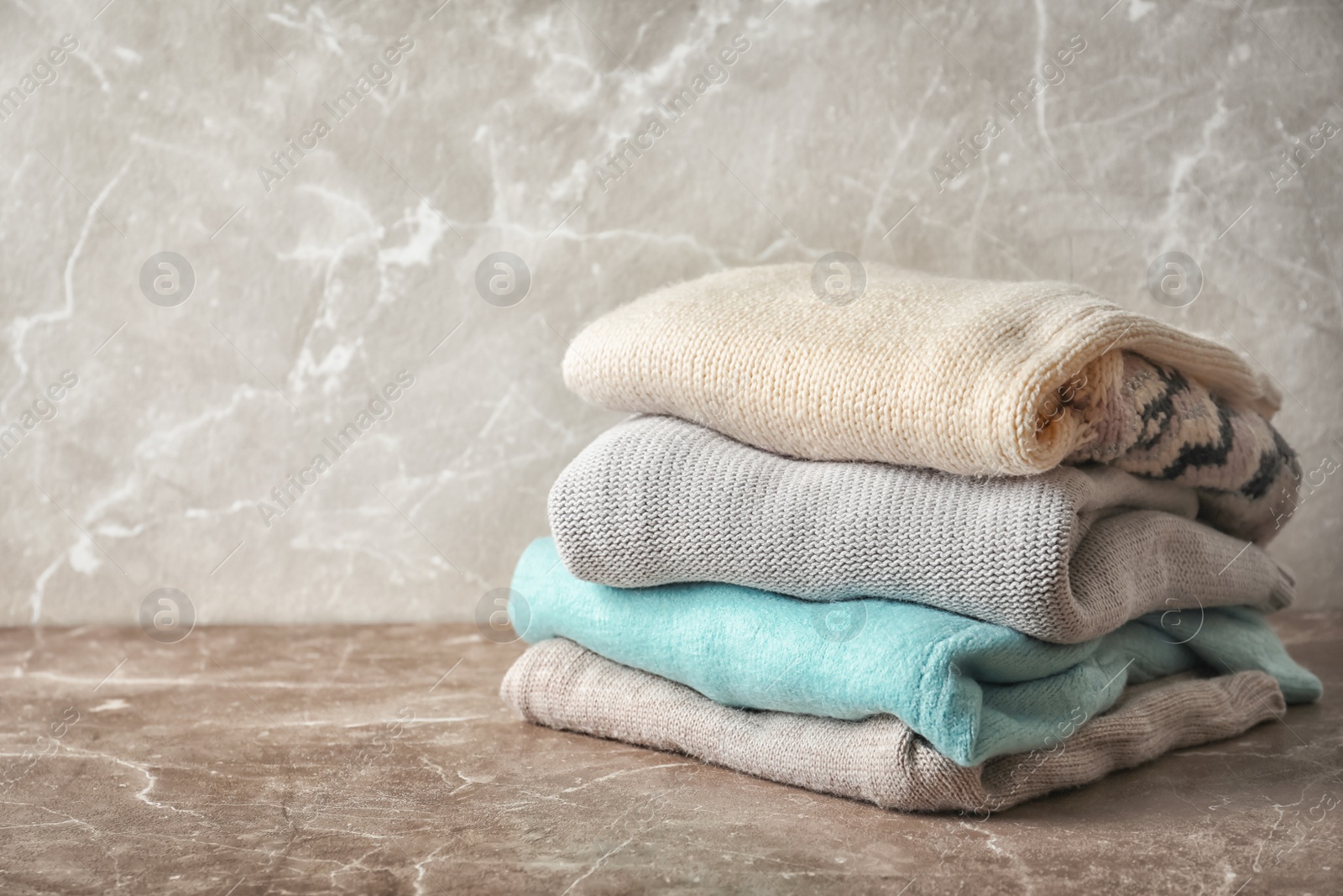 Photo of Stack of warm knitted clothes on table