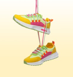 Image of Pair of stylish sneakers in air on color gradient background
