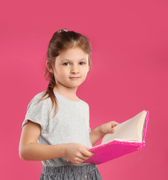 Little girl with book on pink background