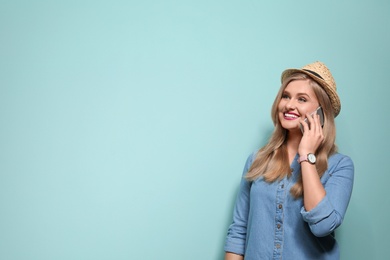 Attractive young woman talking on phone against color background