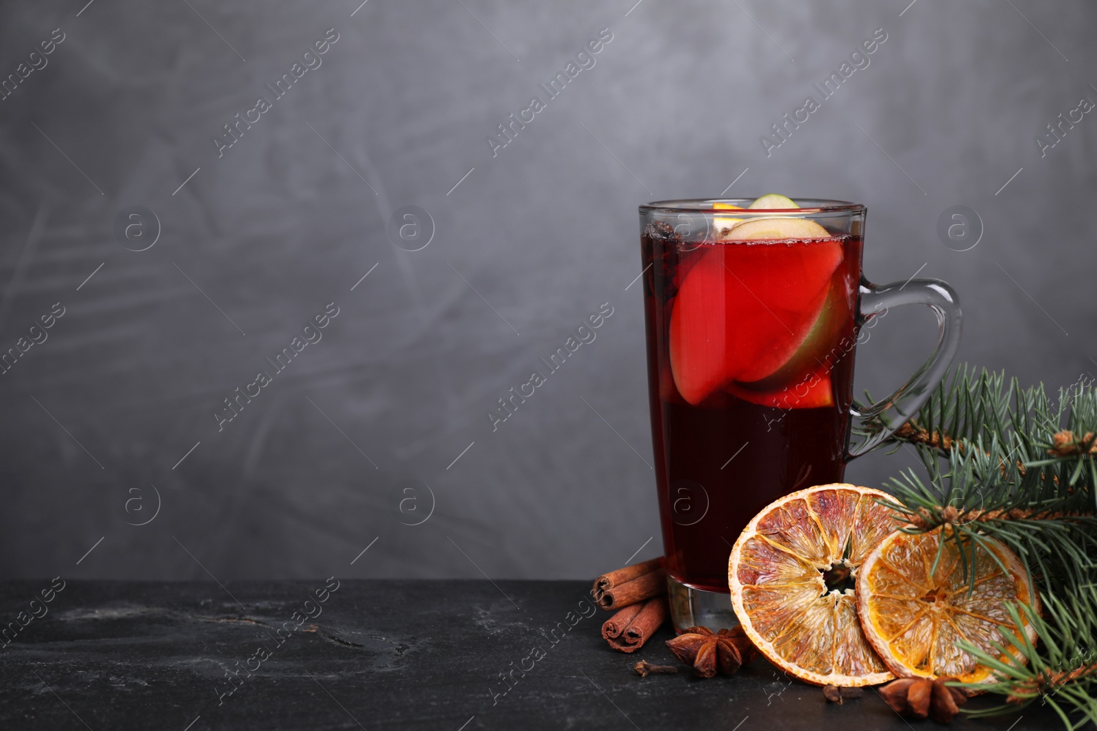 Photo of Tasty aromatic mulled wine on black table, space for text